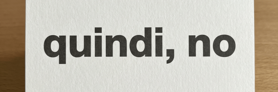 A white card with the text 'quindi, no' in black letters on a wooden table.