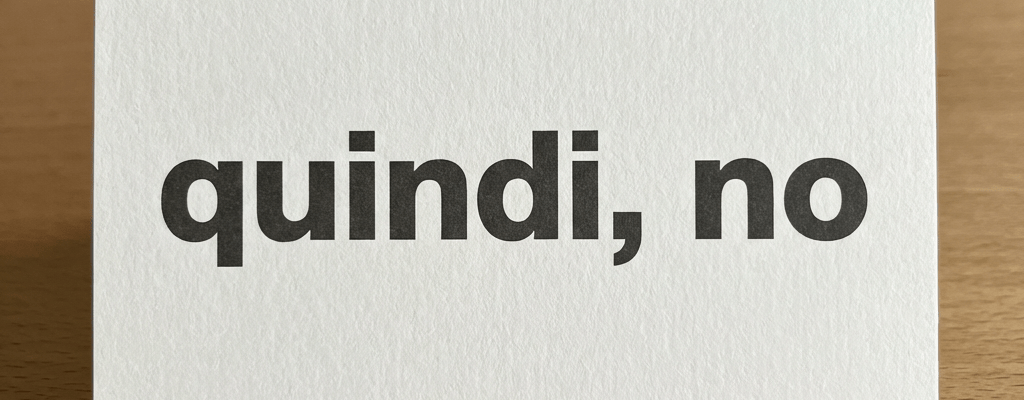 A white card with the text 'quindi, no' in black letters on a wooden table.