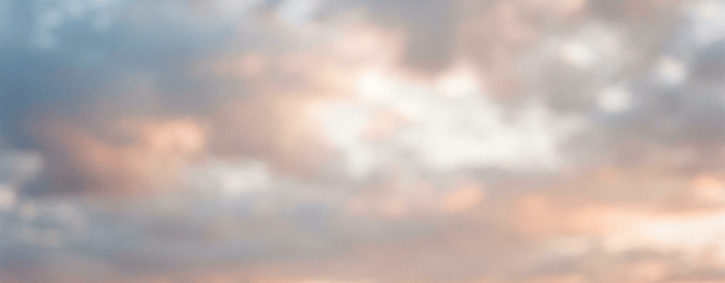 Soft sunset over rolling countryside beneath cloudy skies